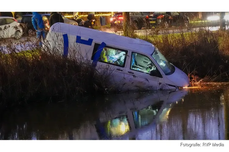 Bedrijfsbus ramt verkeerspaal en belandt in het water
