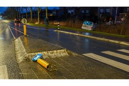 Bedrijfsbus ramt verkeerspaal en belandt in het water